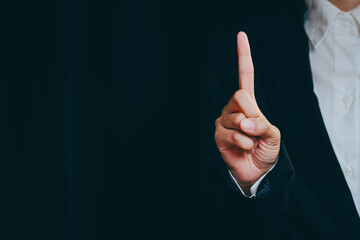 Person Wearing Suit Indicating One With Finger in Dark Setting, business concept