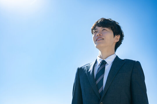 空に向かって立つスーツを着た男性