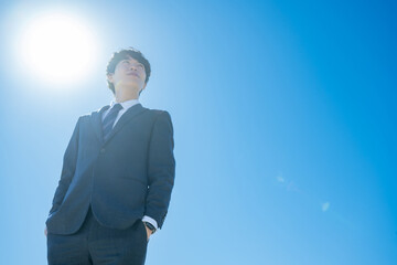 空に向かって立つスーツを着た男性