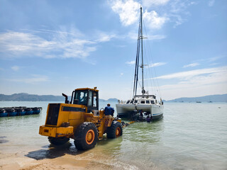Yellow tractor is pulling a boat out of the water in a beautiful coastal area