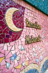 Ramadhan Mubarak written on a pink wall. Islamic holy month celebration. Vertical (2:3)
