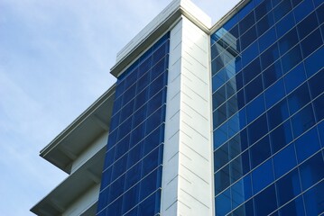 Obraz premium low angle of modern office building with blue glass window facade and white wall