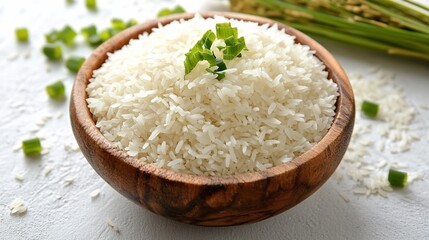 Cooked rice in wooden bowl, green onions, rice stalks, white background; food photography