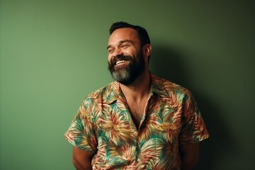 Fototapeta premium Portrait of a handsome bearded man smiling at the camera. Green background.