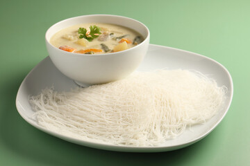 Idiyappam, Traditional South Indian Dish served with vegetable curry on green background 
