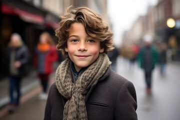 Fototapeta premium portrait of a cute young boy in a coat and scarf on the street