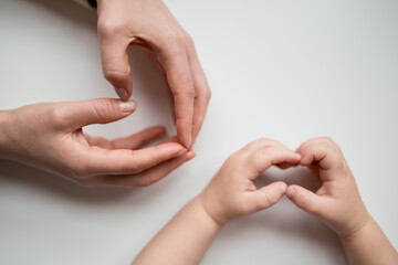 Adult and child hands forming hearts on white background