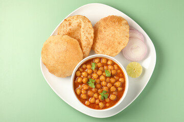 Indian Dish Chole Puri in white ceramic bowl on green background. 