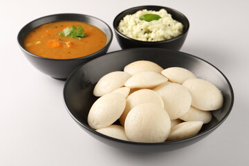 Idli Sambar, Famous South Indian Dish in a black ceramic cutlery on white background