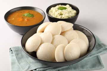 Idli Sambar, Famous South Indian Dish in a black ceramic cutlery on white background