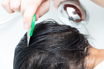 Doctor using a lice comb on patient's wet hair for head lice treatment