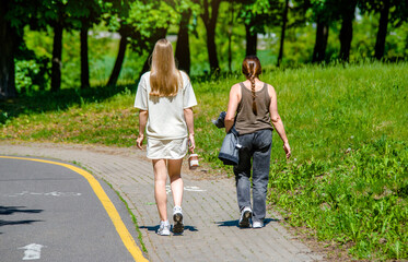 Obraz premium Two girlfriends walk along a path in the Park 