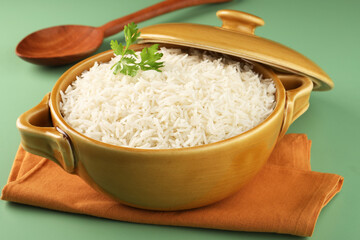 Rice in ceramic cutlery on green background