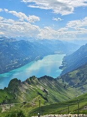 A breathtaking summer photo taken from the summit of Brienzer Rothorn, showcasing the serene beauty of Lake Brienz nestled in the Swiss Alps. The turquoise waters of the lake contrast beautifully with