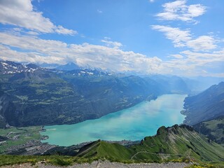 A breathtaking summer photo taken from the summit of Brienzer Rothorn, showcasing the serene beauty of Lake Brienz nestled in the Swiss Alps. The turquoise waters of the lake contrast beautifully with