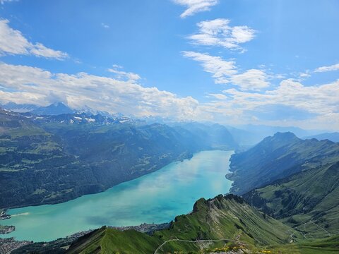A breathtaking summer photo taken from the summit of Brienzer Rothorn, showcasing the serene beauty of Lake Brienz nestled in the Swiss Alps. The turquoise waters of the lake contrast beautifully with
