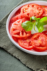 Salad Plate with Ripe Tomato Slices and Fresh Basil on Green Napkin, Close-Up
