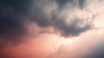 Obraz premium A dramatic cloudscape at sunset with dark storm clouds illuminated by a soft, ethereal pink light.