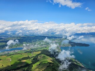 A stunning summer view from Mount Rigi, often referred to as the "Queen of the Mountains," offering panoramic vistas of the Swiss Alps and surrounding lakes. This image captures the lush green meadows