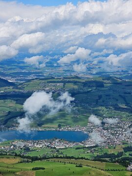 A stunning summer view from Mount Rigi, often referred to as the "Queen of the Mountains," offering panoramic vistas of the Swiss Alps and surrounding lakes. This image captures the lush green meadows