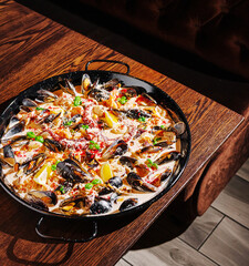 Delicious seafood paella served on a wooden table in a cozy setting