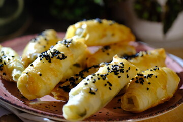 Homemade hot snack, delicious spring rolls with cheese, black cumin and sesame seeds. Ramadan iftar table. Traditional Turkish cuisine flavors. Pastries. Close-up.