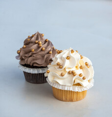 A duo of gourmet cupcakes with creamy frosting and golden decorations, minimal setting