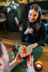 Boyfriend gives his girlfriend a gift on a romantic dinner date in a restaurant.