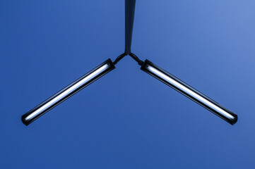 Symmetrical Neon Fluorescent Lights Against Clear Blue Sky in Urban Setting