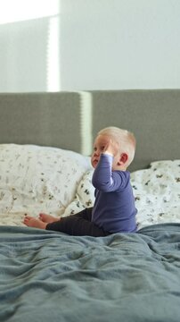 Cute smiling boy 1 year old lying in bed and playing. Child playing while lying on bed. Smiling boy in bedroom.