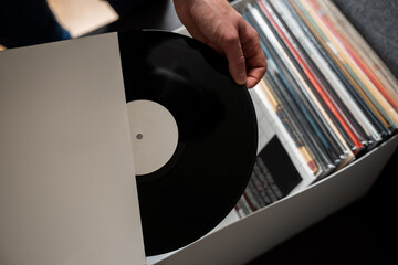Vinyl music lover is selecting rock vinyl album from collection. Listen to music at home....