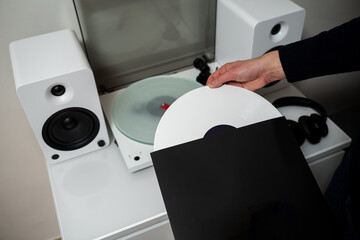 Vinyl LP tracks with modern needle player. Musician changes vinyl record into turntable player and...