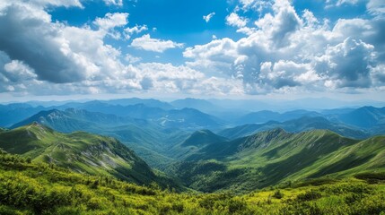 Naklejka premium A mountain range stretches out before you, with fast-moving clouds above. The green plants and blue sky create a beautiful summer landscape.
