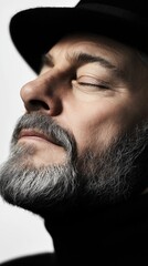 Obraz premium Focused man with a gray beard enjoying a moment of peace and contemplation in soft lighting