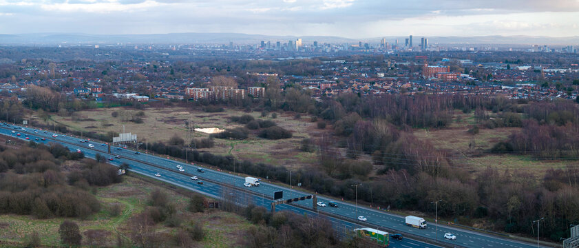 Panoramic aerial image of M60 Manchester outer ring road near Swinton with Manchester skyline on the horizon. 