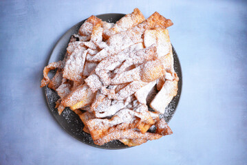 Tradycyjne polskie faworki (chrust) posypane cukrem pudrem – chrupiące ciastka karnawałowe, popularne podczas Tłustego Czwartku i świąt.
Traditional Polish faworki (angel wings) with po
