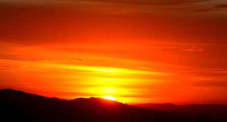 Distant mountain range silhouetted against a fiery sunset background. Nature's beauty framed in brilliant hues