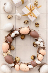 Easter composition with festive wreath made of eggs on white tile table