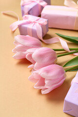 Gift boxes and pink tulips on beige background. Closeup