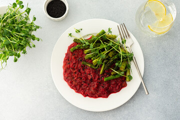 Beetroot risotto with rice and sesame seeds, baked asparagus with microgreens