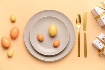 Beautiful Easter table setting with gifts and eggs on orange background