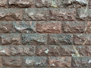 Background in the form of a wall of textured brick and tuff in red, black and gray colors with white tsaramins