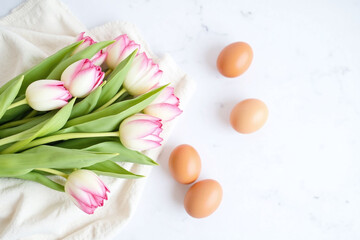 White pink tulips with brown eggs on light colored napkin