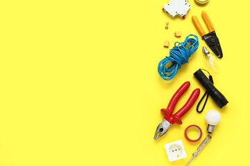 Electrician's tools, light bulbs and electronics on yellow background