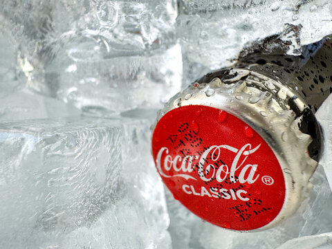 Coca Cola classic bottle and cap close up with ice on the background