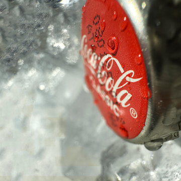 Coca Cola classic bottle and cap close up with ice on the background