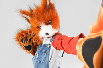 Quadrober girl in fox mask taking selfie on light background