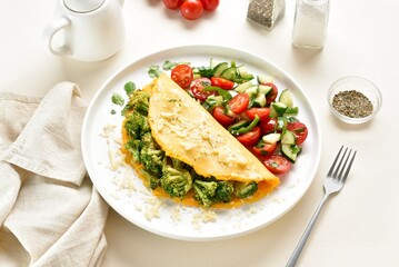 Omelet with roasted broccoli and cheese served with salad from fresh vegetables