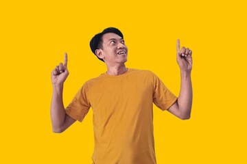 A young Asian man in a yellow shirt looks surprised, pointing enthusiastically at something...