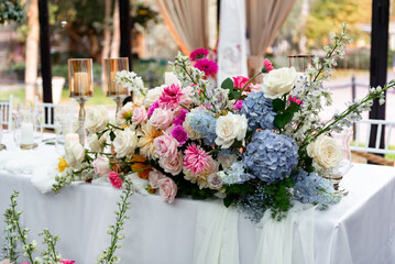 Vibrant floral arrangement graces elegant outdoor dining setting on a sunny afternoon